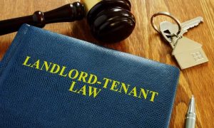 A wooden desk holds a blue leather book on landlord and tenant law that spells out tenant privacy rights