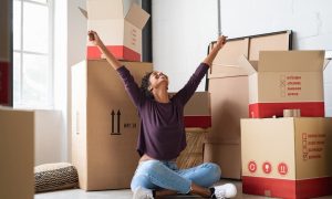 Excited woman sitting cross-legged on the floor in her new home, a result of rent concessions.