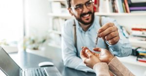 A landlord confidently hands new tenants the keys after screening them with online tenant screening software